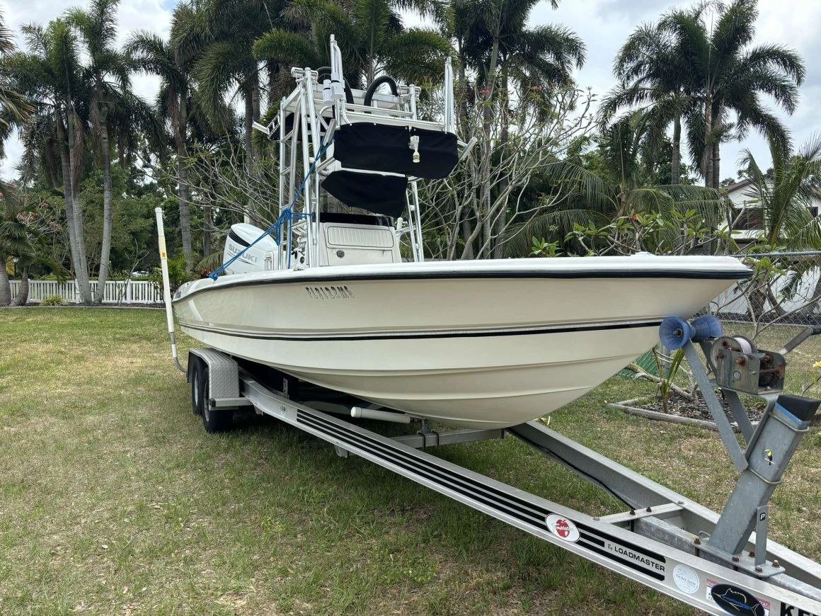 A centre-console boat on its trailer under palms