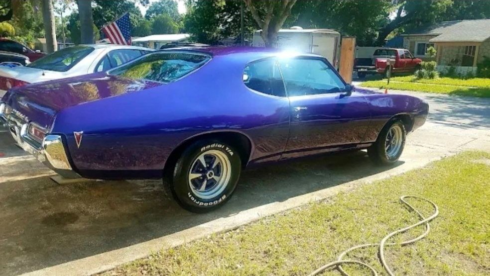A purple classic muscle car on grass